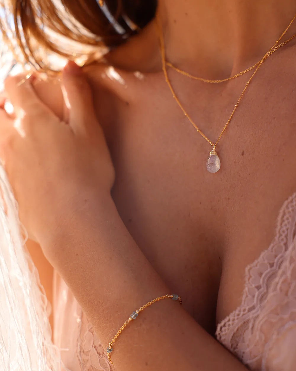 Model wearing necklace featuring a faceted Moonstone gem, wrapped in fine gold-filled wire and suspended from a delicate ball chain