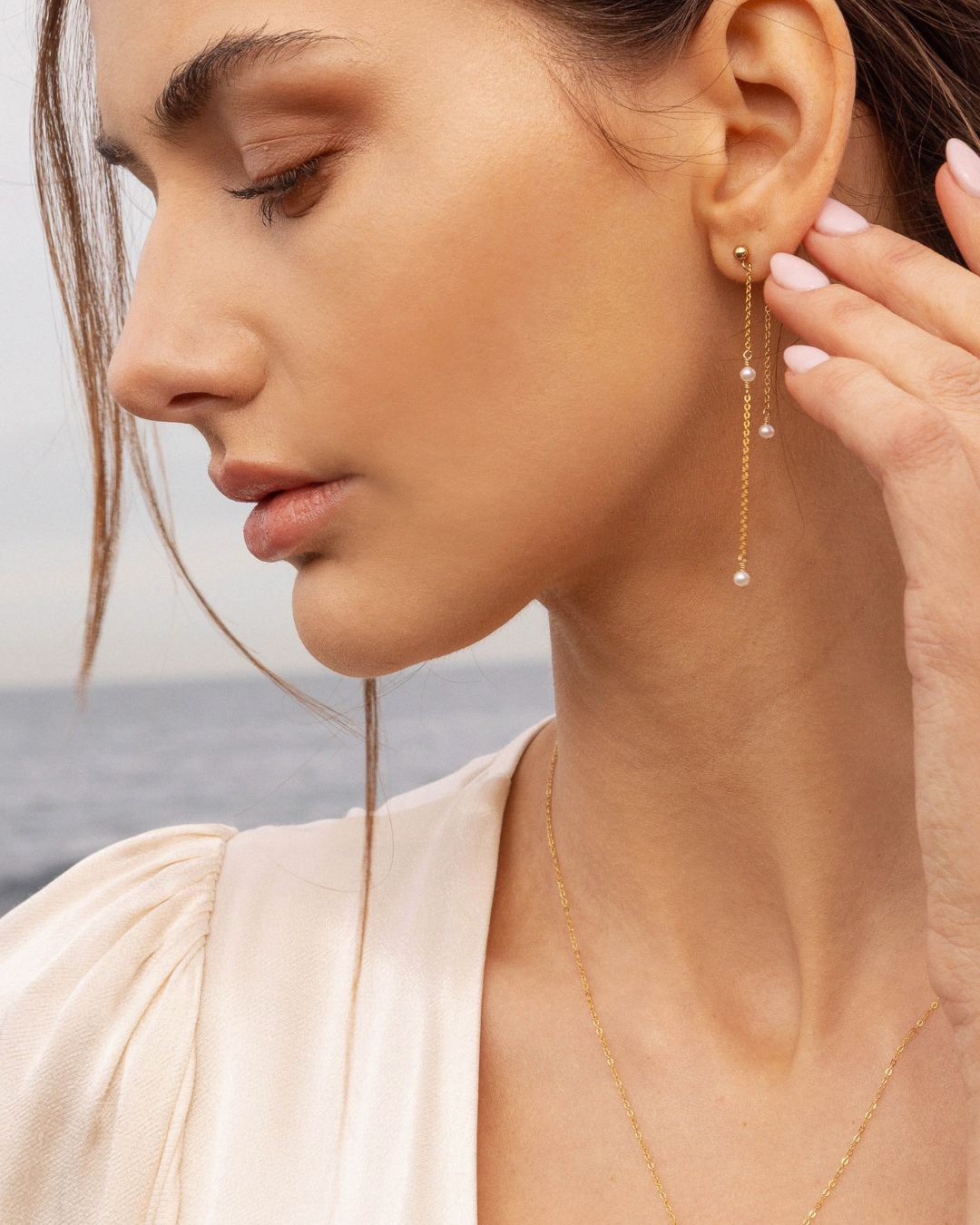 Close-up of a woman wearing a gold pearl earring with a blurred background