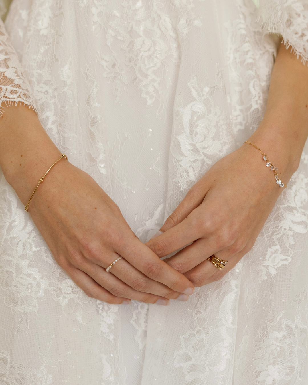 Close-up of the hands of a bride in wedding dress with gold and Cubic Zirconia jewellery.
