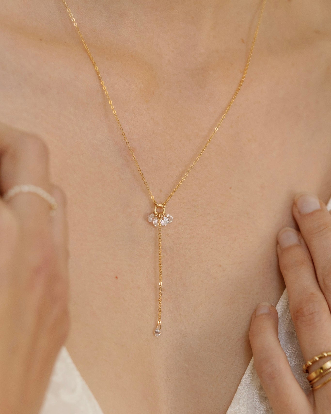 Close-up of a bride's neck wearing a gold lariat cubic zirconia necklace 