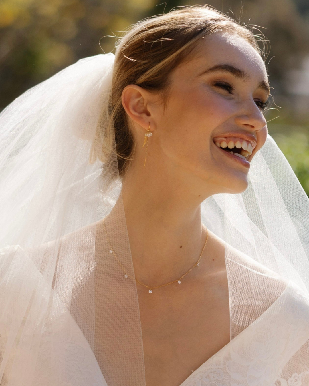 Bride wearing a wedding dress and veil with gold cubic zirconia gemstone jewellery outdoors