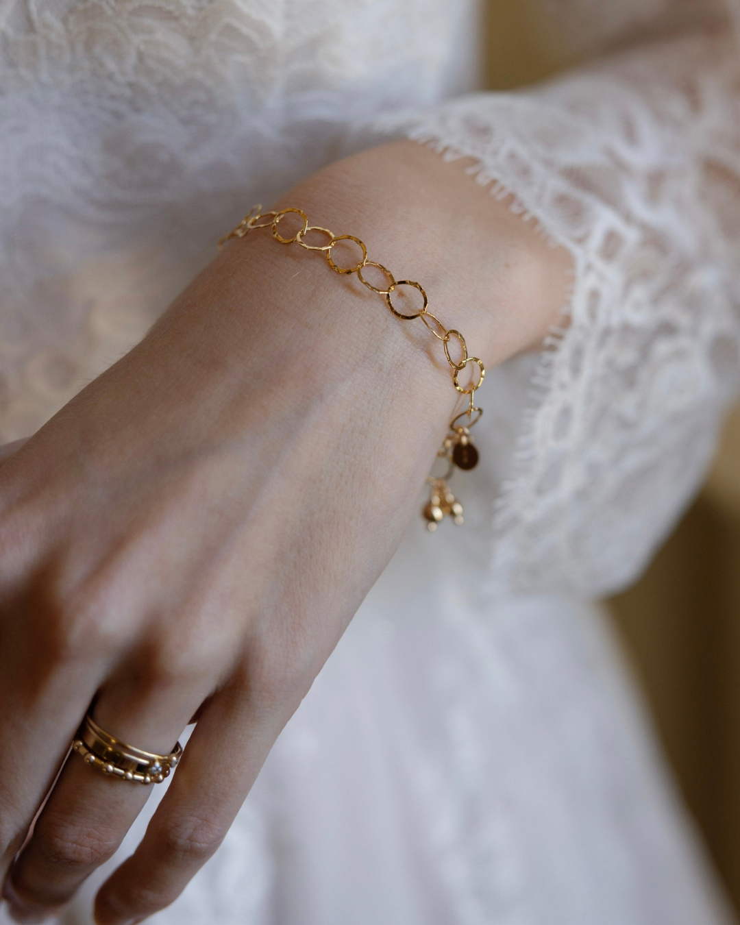 Gold bracelet on a bride's wrist against a blurred white background