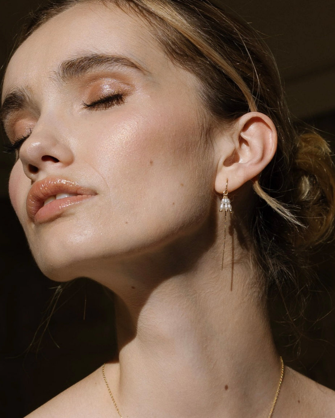 Close-up of a woman wearing elegant pearl earrings with a dark background