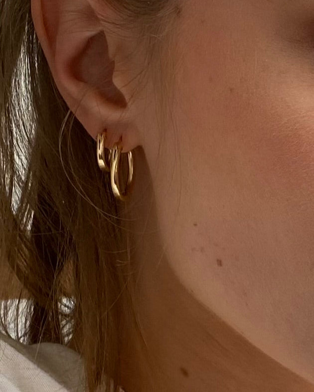 Close-up of a person wearing gold hoop earrings