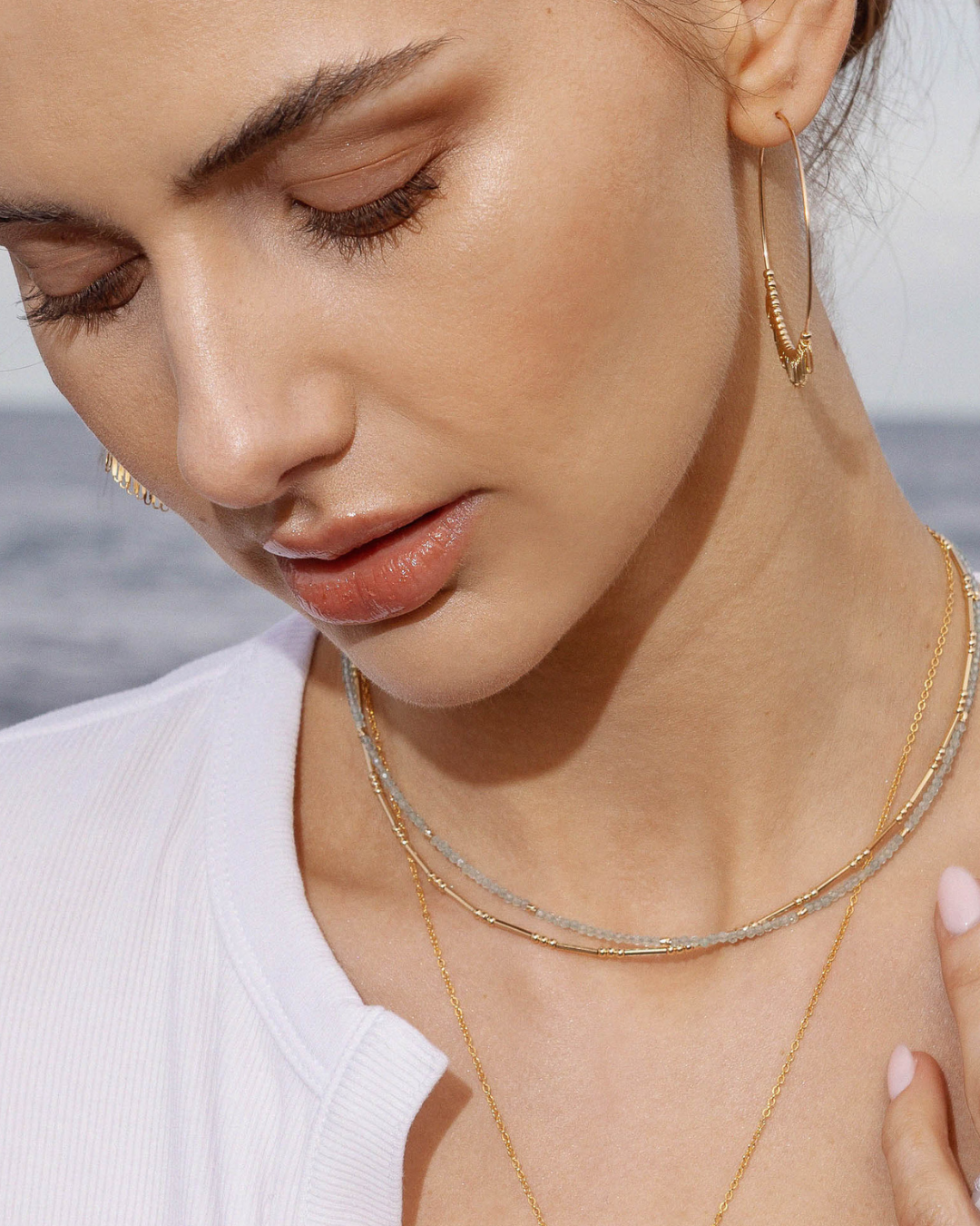 Close-up of a woman wearing gold hoop earrings and necklaces with a blurred background