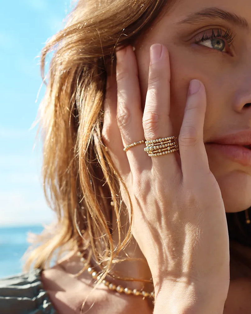 The Codie ring features an alternating pattern of round and tube gold beads, hand-threaded onto durable stretch cord.