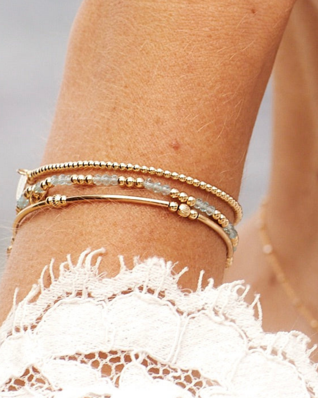 Gold stack of bracelets on a wrist with a blurred background
