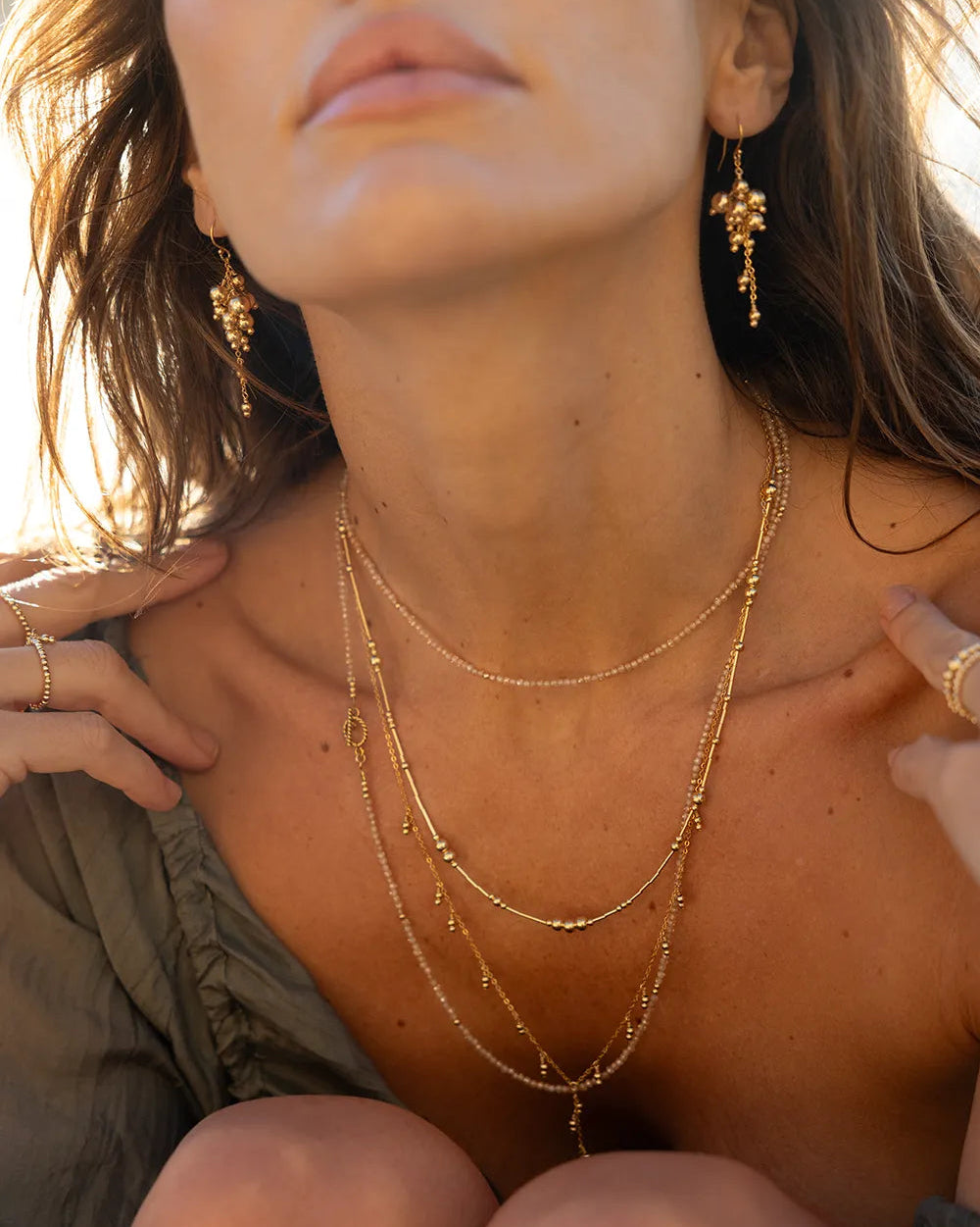 Model wearing necklace with fine gold tubes and smooth round gold beads in varying sizes