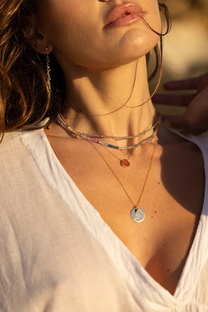 Model wearing Necklaces with Sapphire gems in shades of pink, green, yellow, blue, and white, delicately interspersed with gold accent beads.