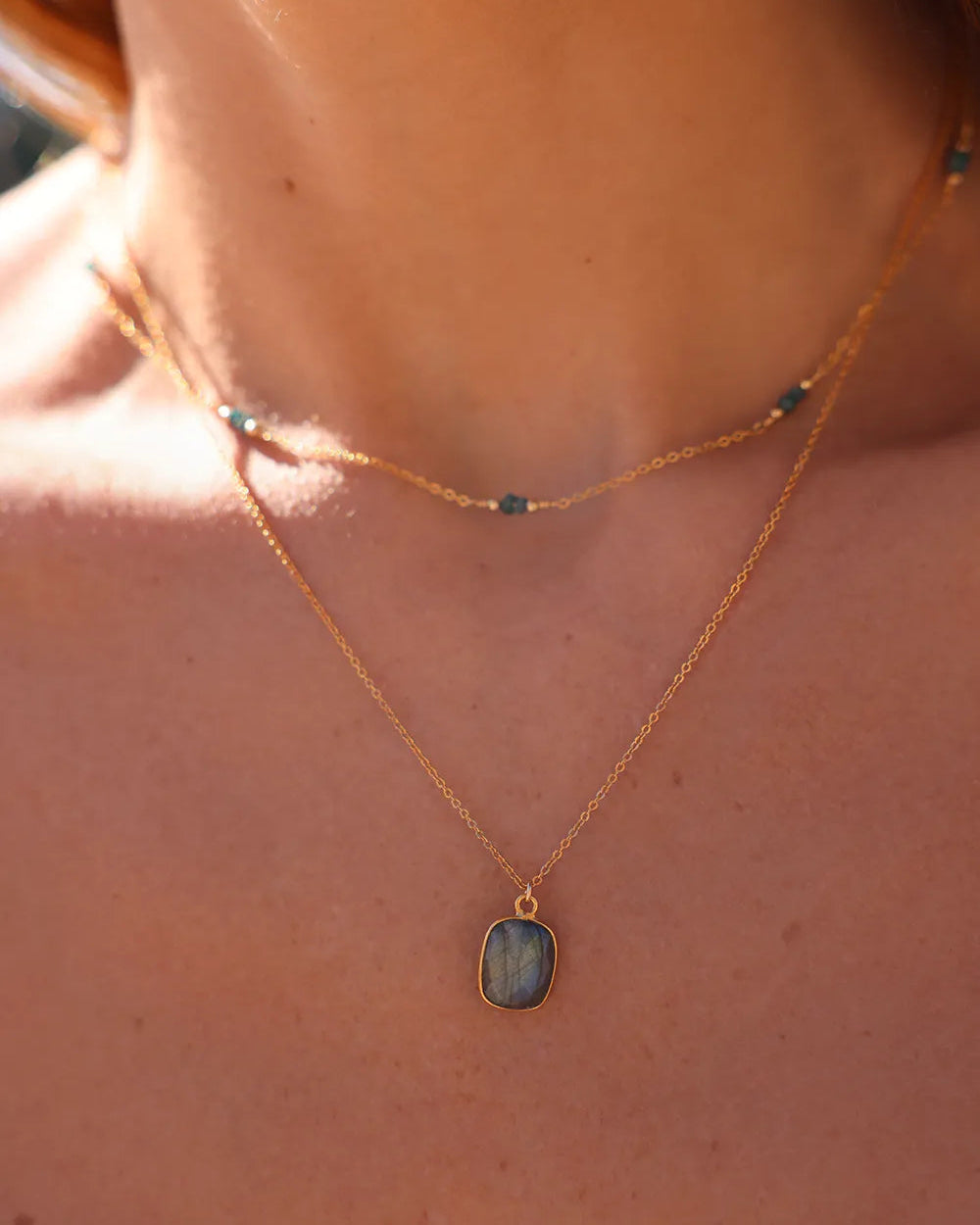 Model wearing Gold necklace wth blue raw diamond gemstones, paired with gold beads.