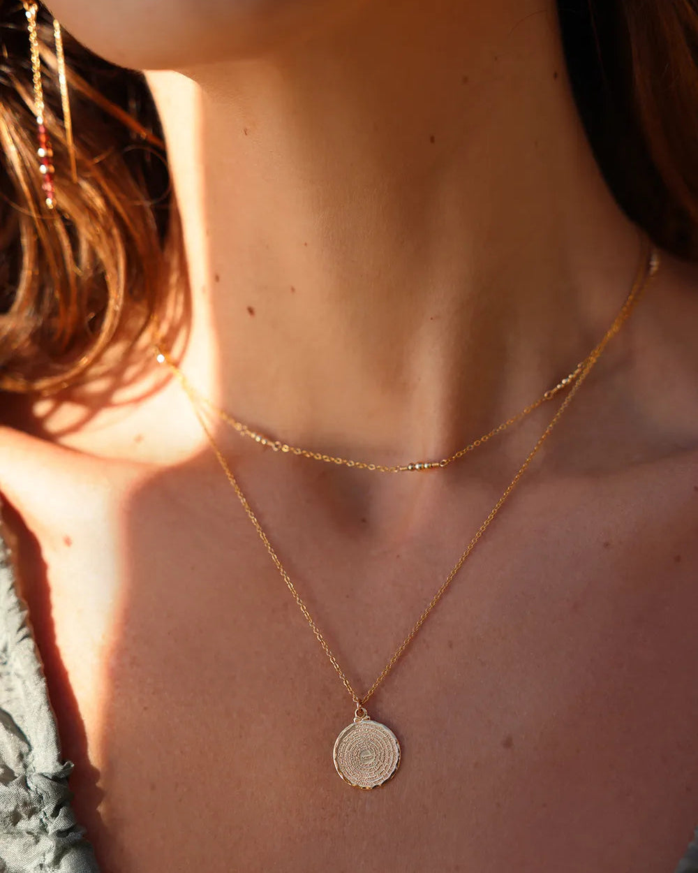 Model wearing necklace with radiant gold beads, meticulously hand wire wrapped along a fine gold chain