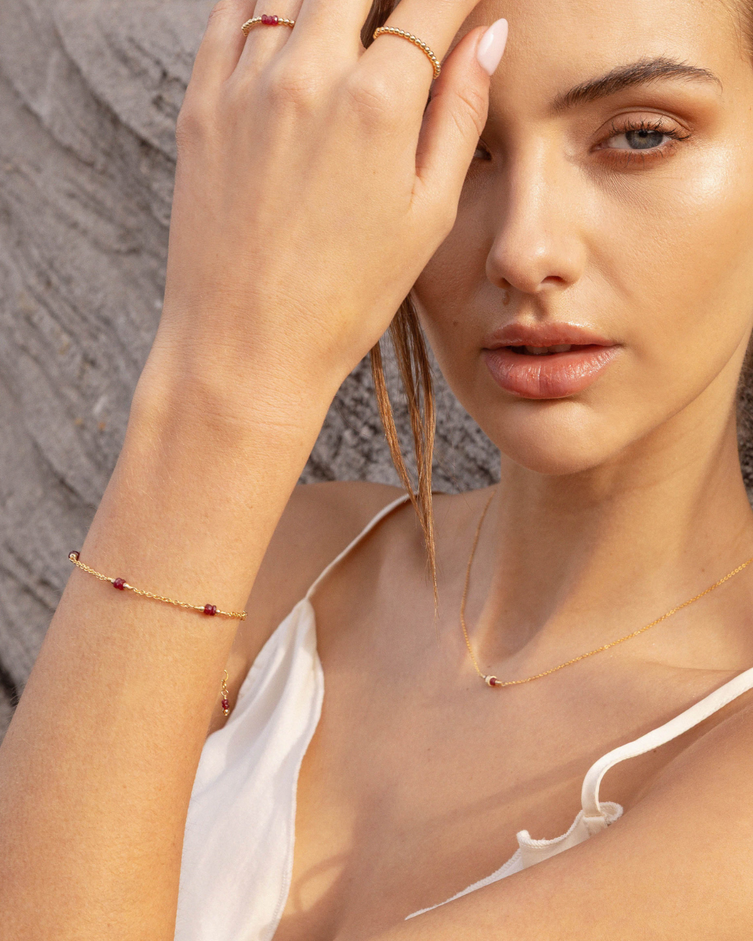 Woman wearing gold ruby jewellery with a neutral background