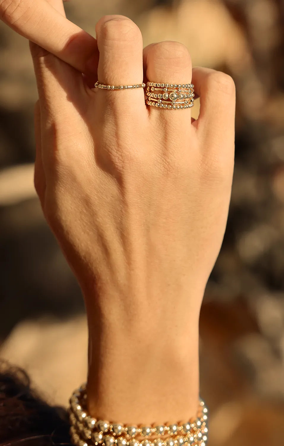 Hand wearing ring with gold beads, hand-threaded onto durable jewellery stretch cord.