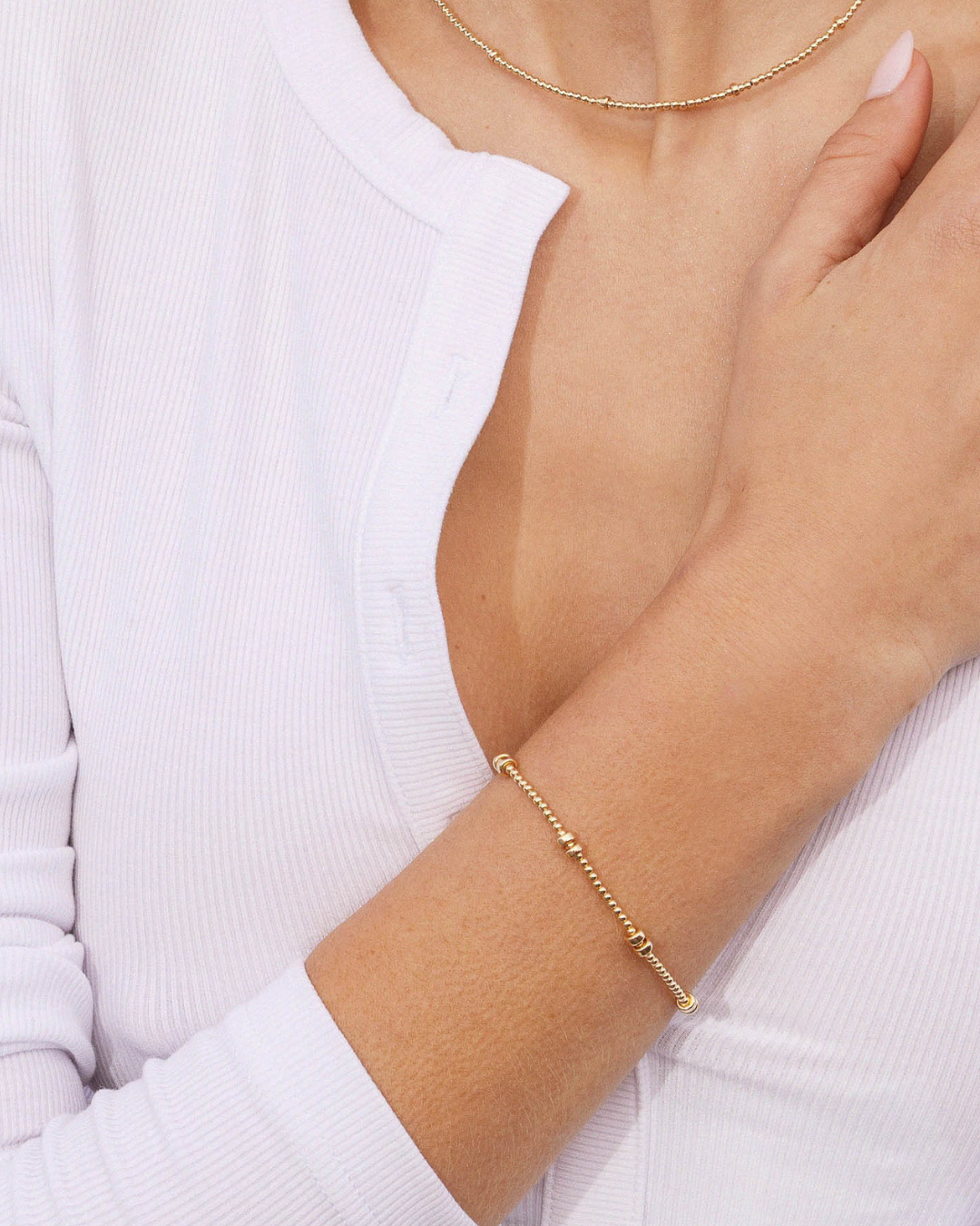 Gold bracelet on a person's wrist with a white background