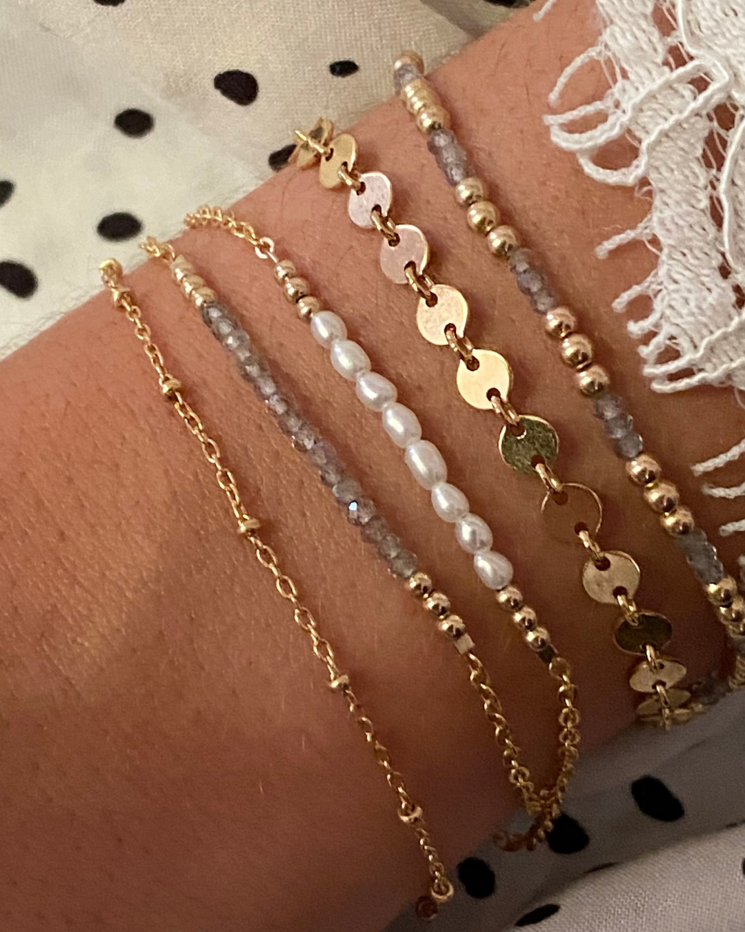 Multiple labradorite bracelets on a wrist with a polka dot fabric background