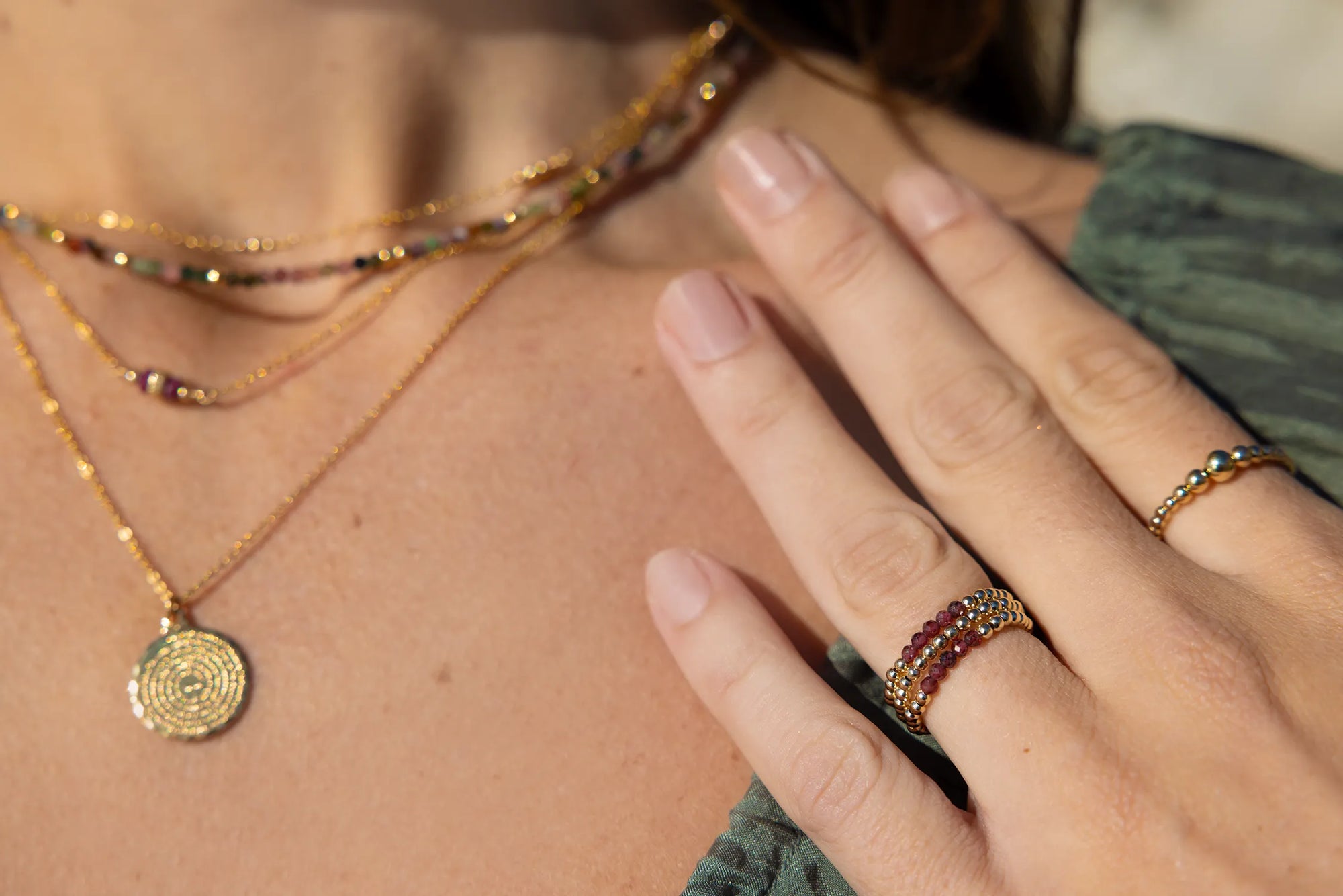 Model wearing gold and garnet beaded rings