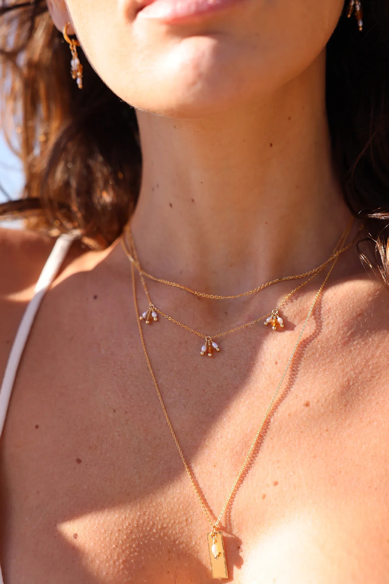 Model wearing Gold necklace with a rectangular pendant and pearl drop