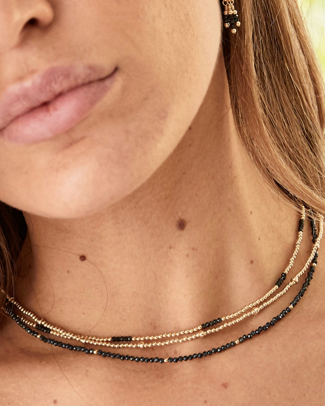 Layered gold and black gemstone beaded necklaces.