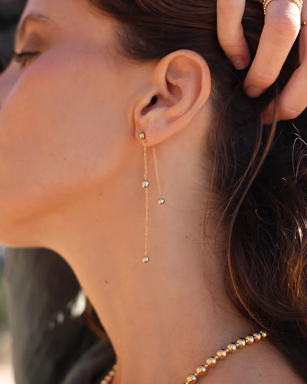 Model wearing Gold chain earrings with gold beads in a sleek, asymmetric design