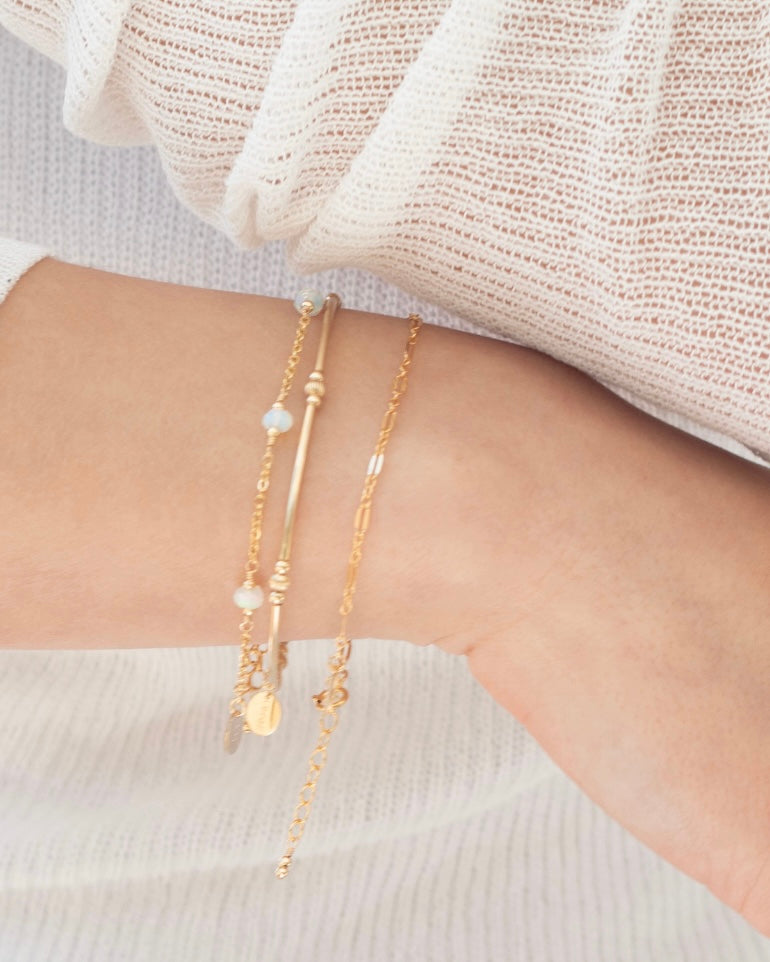 Gold bracelets on a wrist with a neutral background