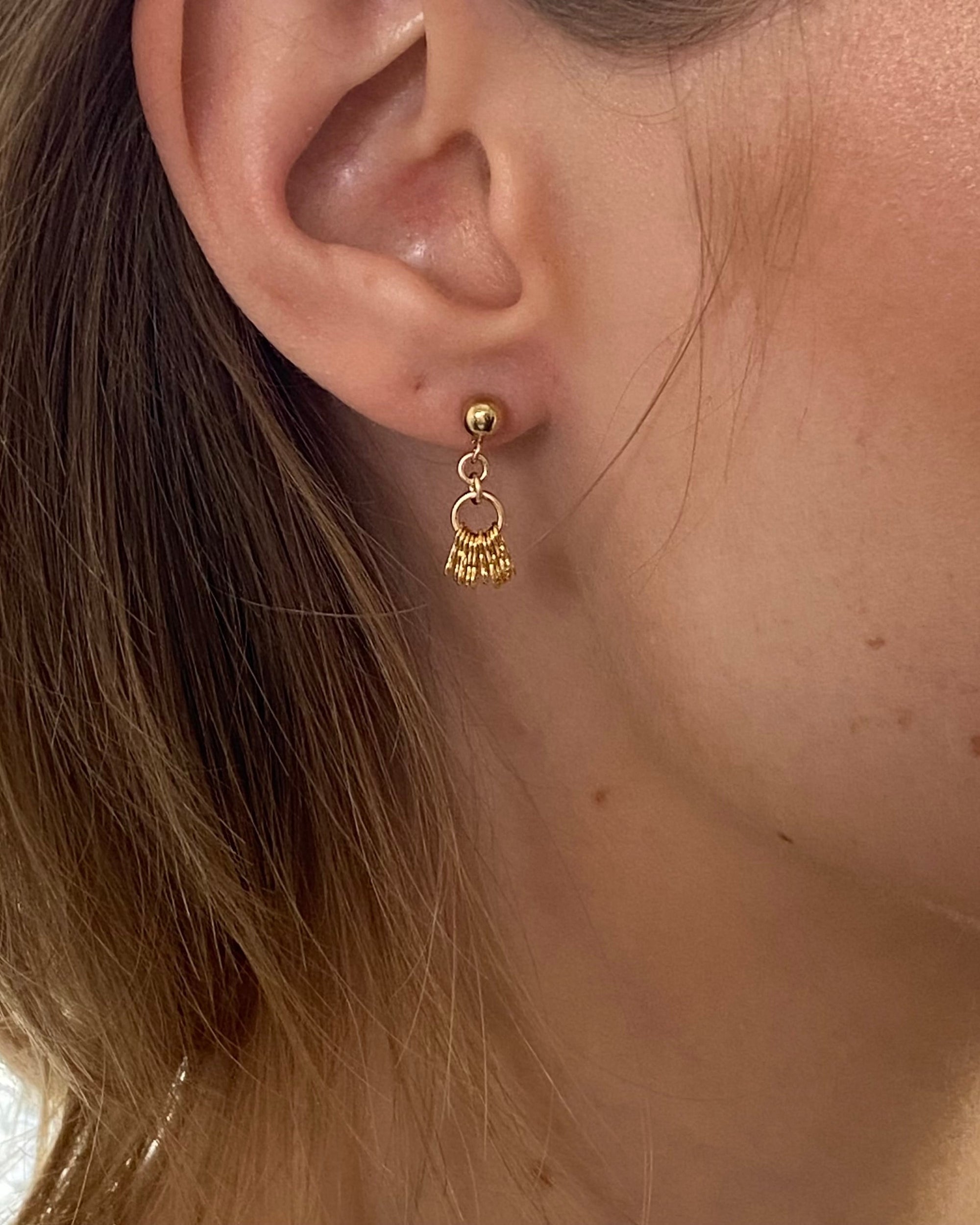Close-up of a person wearing pretty gold earrings 