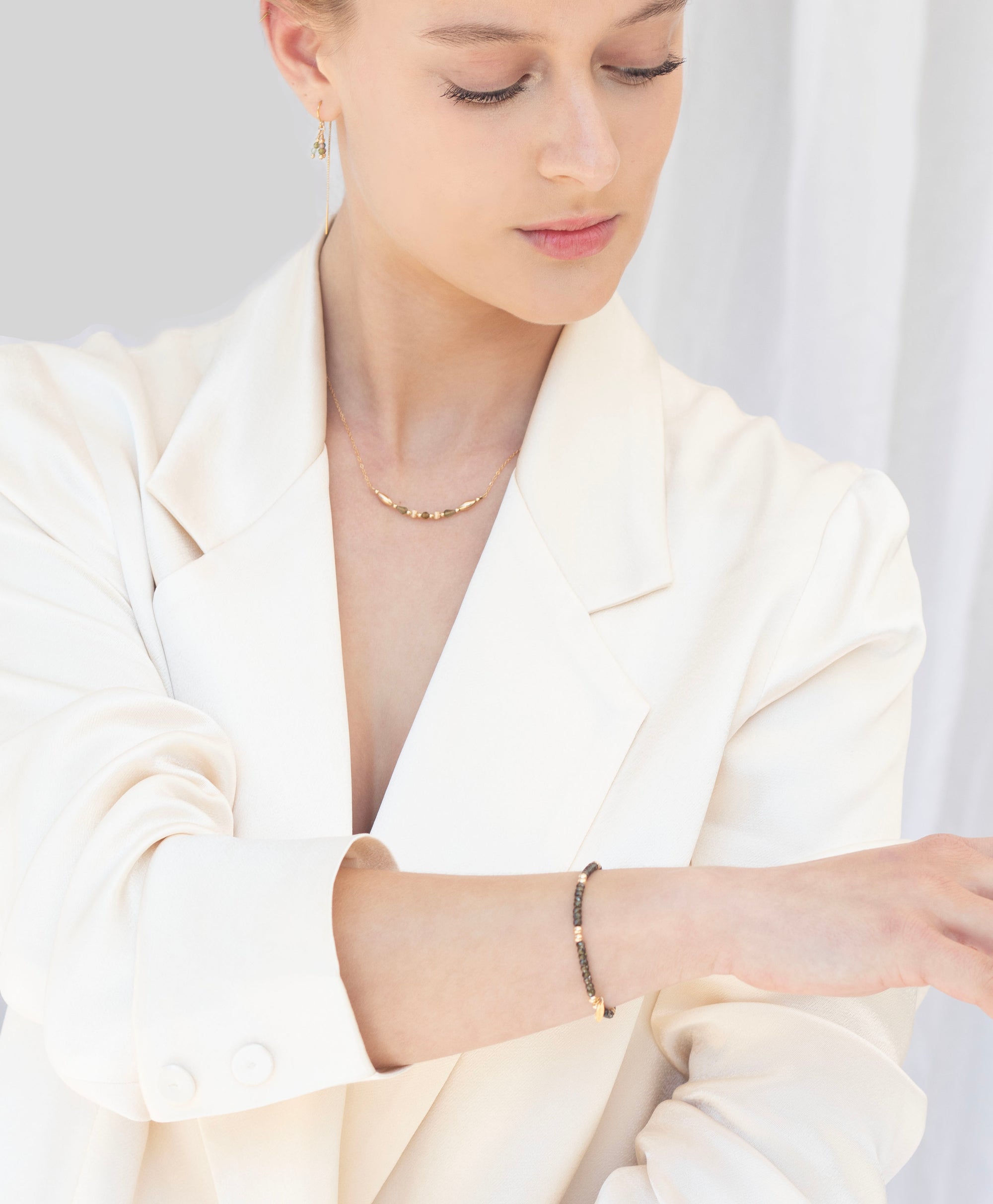 Woman wearing a gold gemstone necklace, bracelet and earrings 