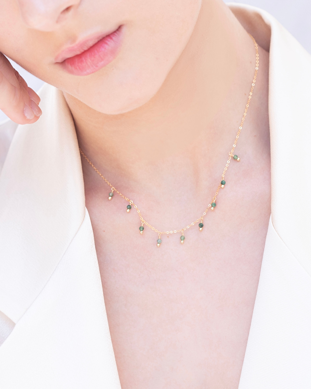 Close-up of a woman's neck wearing a fine emerald gemstone necklace