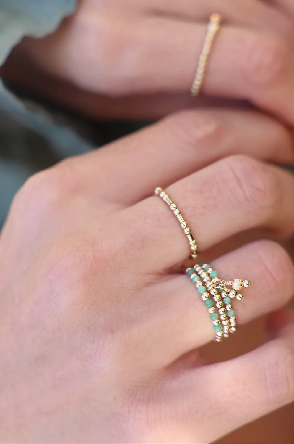 Model wearing ring showcasing a tassel of corrugated gold beads, hand-threaded onto durable stretch cord