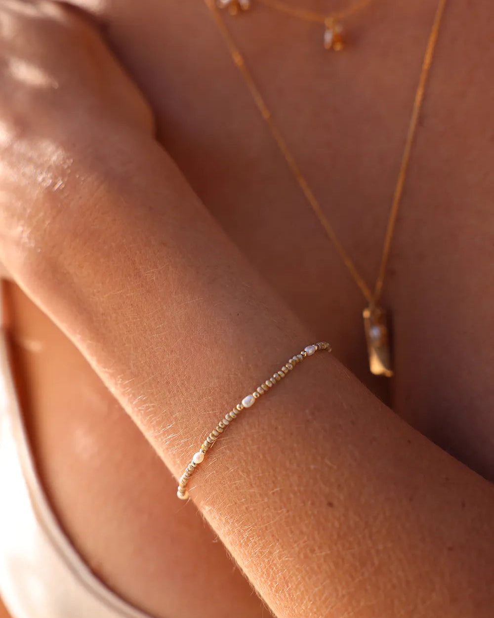 Model wearing delicate Gold and pearl beaded bracelet