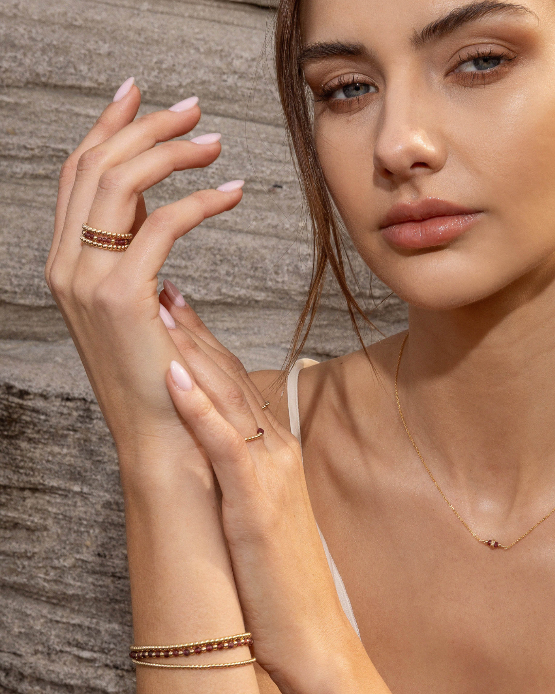 Woman wearing gold jewelry against a wooden background