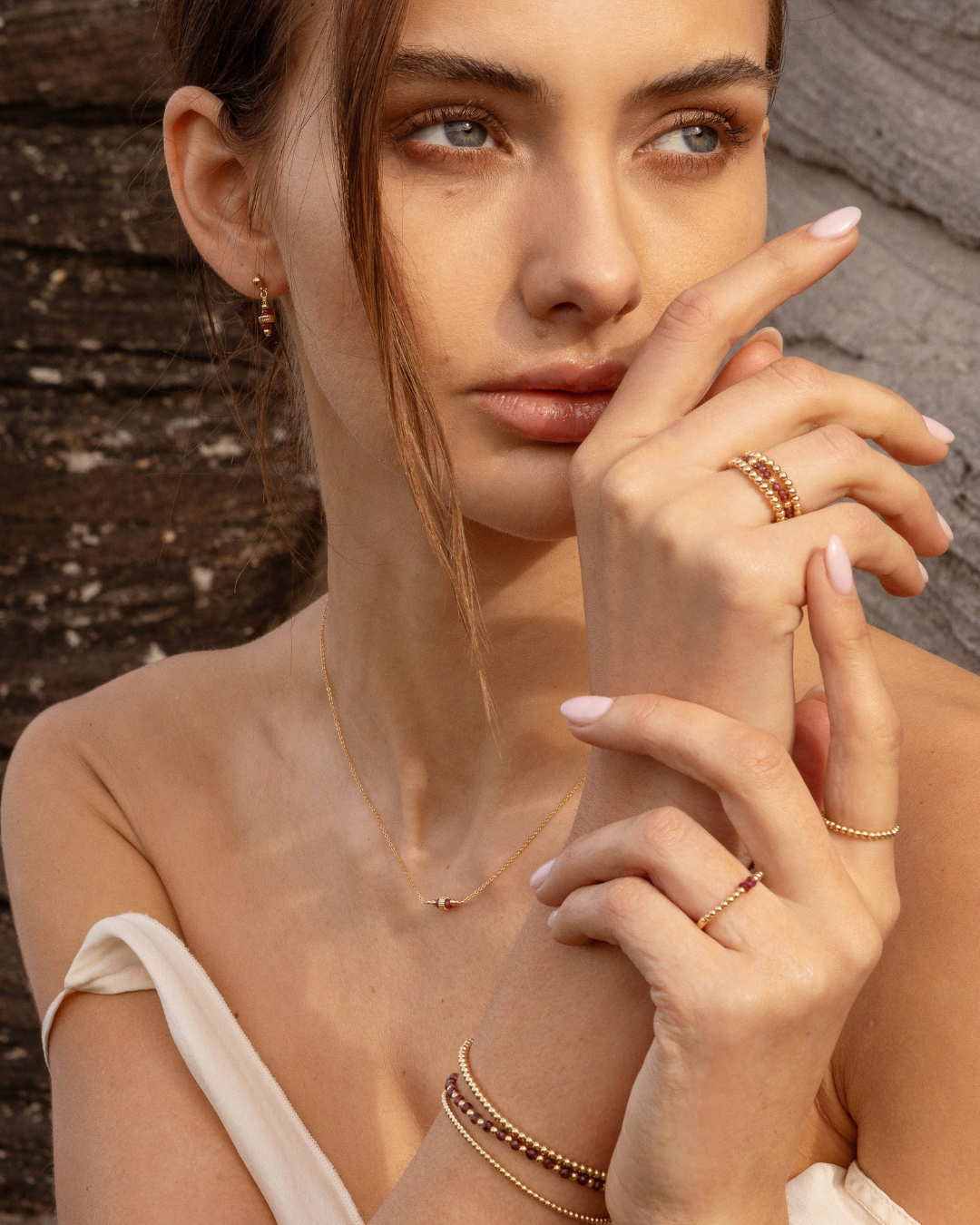 Woman wearing gold ruby earrings and matching necklace with garnet gold beaded rings and bracelets 