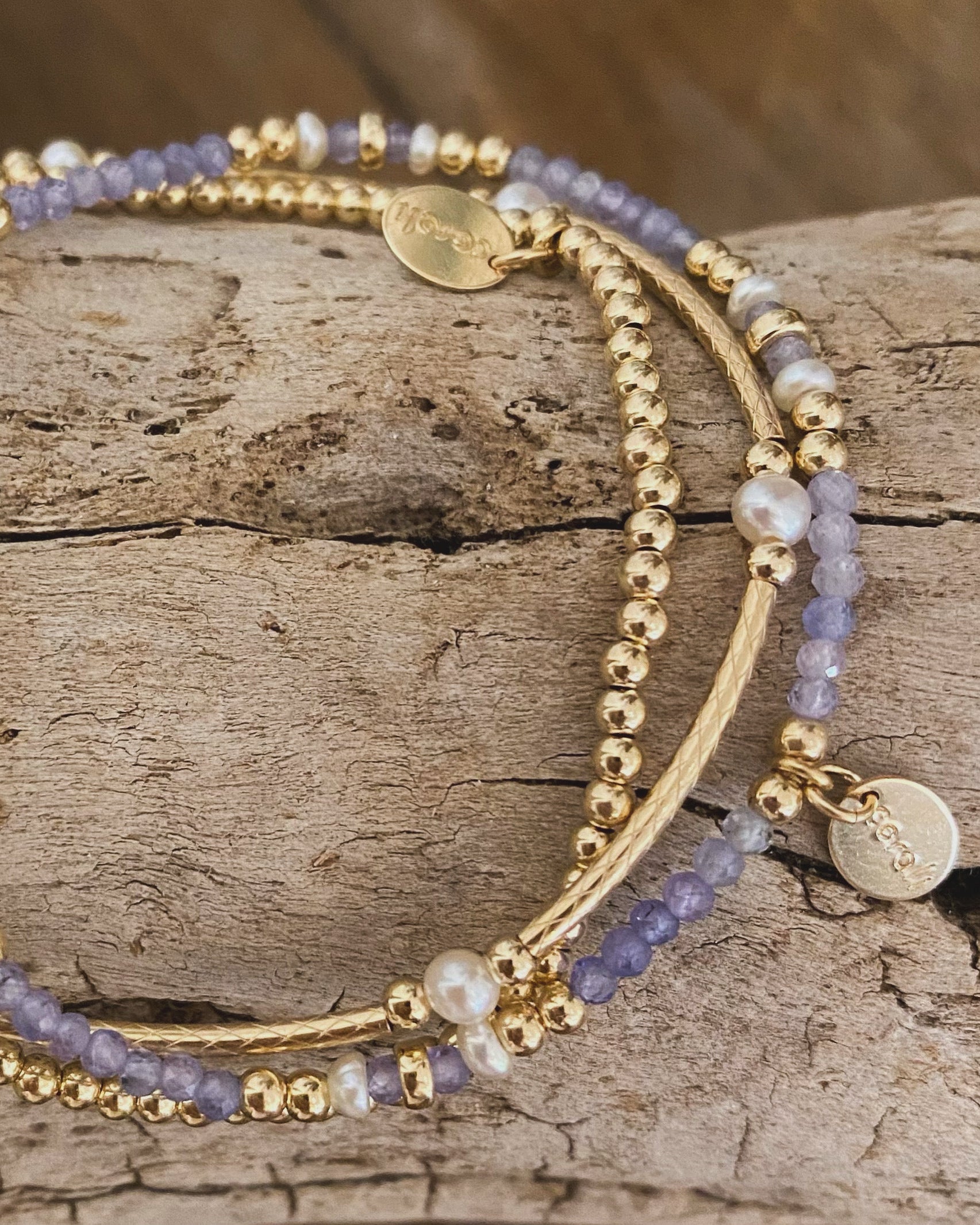 Gold beaded tanzanite gemstone pearl bracelets on a wooden surface