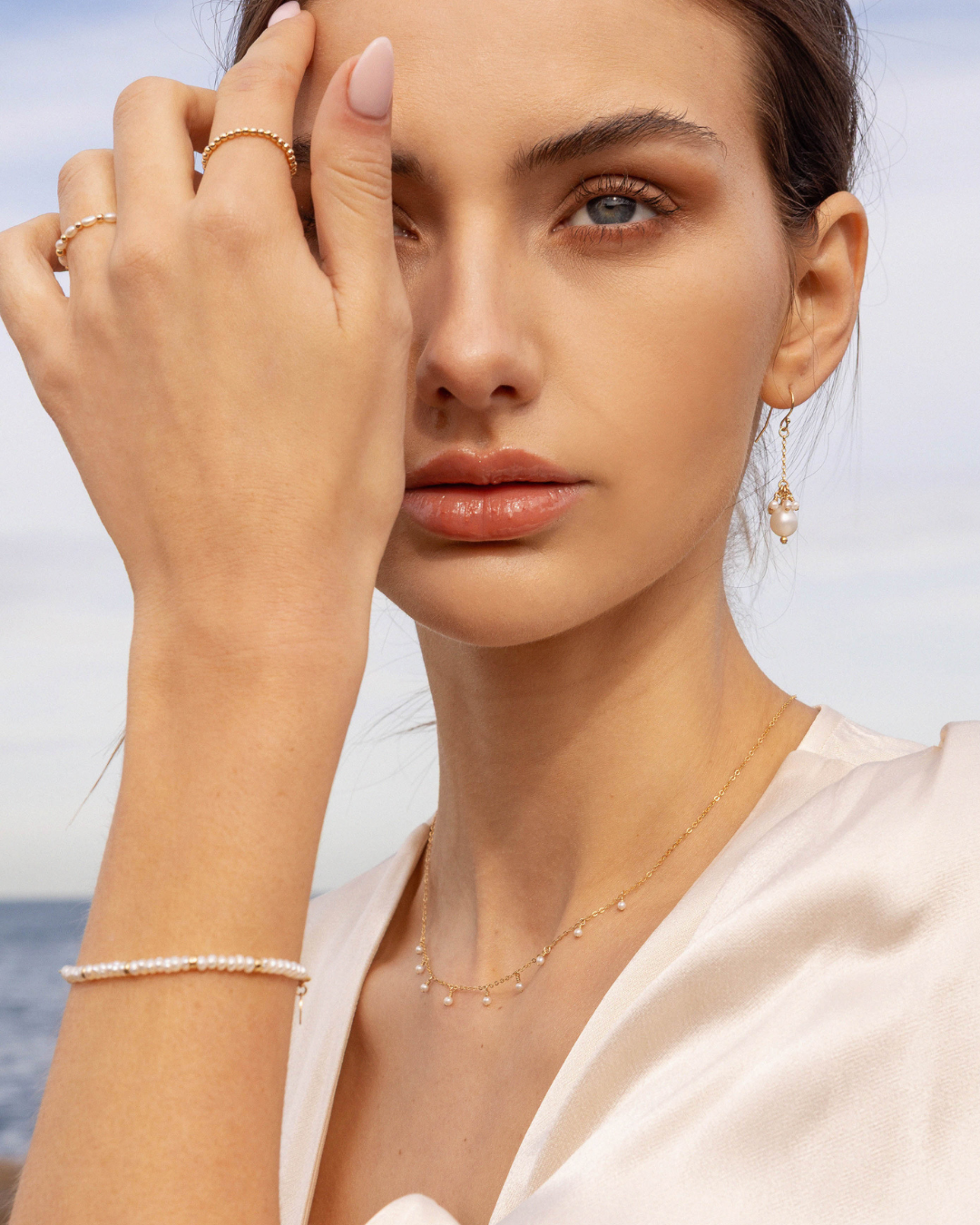 Woman wearing gold pearl jewellery including with a blurred background