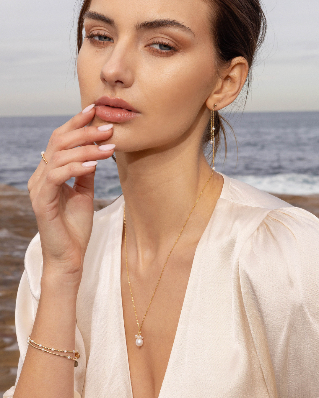 Woman wearing pearl jewellery with a blurred beach background